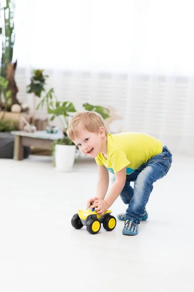 幸せな子供時代の家でおもちゃの車で遊んで少し陽気な少年 — ストック写真