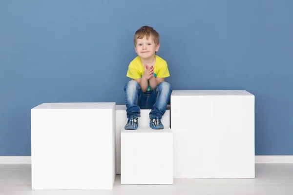 Szczęśliwe dzieciństwo - wesoły chłopiec stwarzające przez niebieską ścianą — Zdjęcie stockowe