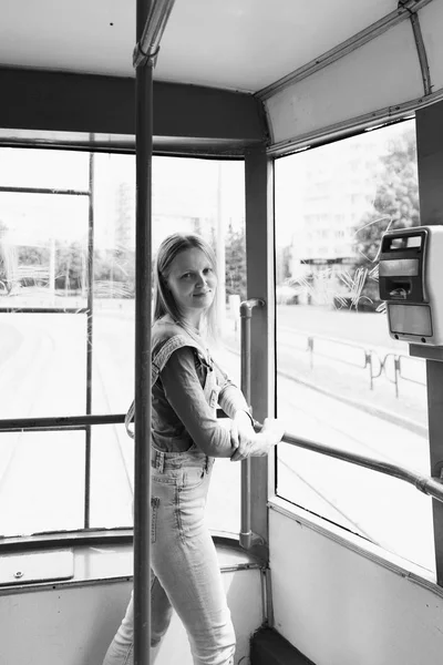 Foto de la calle en el estilo de una vieja película en blanco y negro con grano - una mujer feliz está conduciendo en un viejo tranvía — Foto de Stock