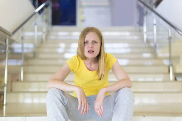 Modern woman in casual clothes sits on store steps — Stock Photo, Image