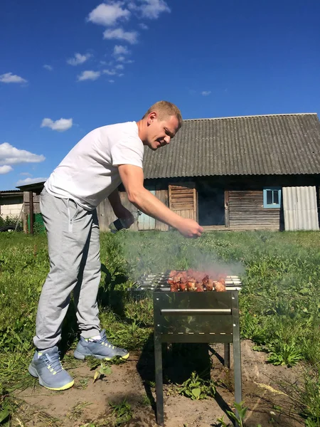 村里的生活--一个年轻人在后院煎羊肉串烤肉串 — 图库照片