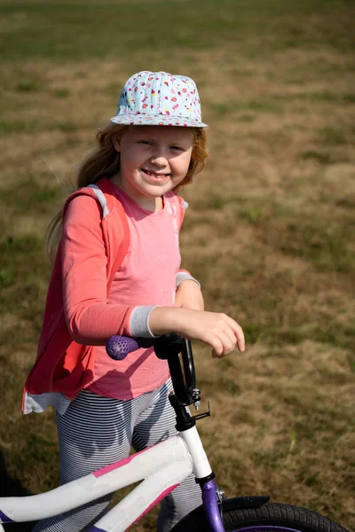 Aktiver Lebensstil moderner Kinder - nettes blondes Mädchen spaziert mit Fahrrad auf dem Feld — Stockfoto