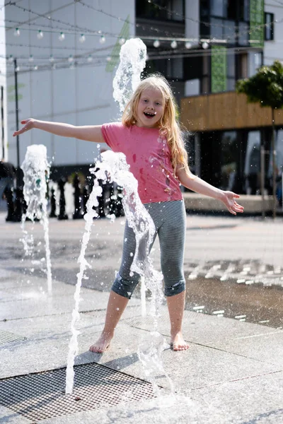 Life of children in a modern city - little girl having fun with fountains — Stock Photo, Image