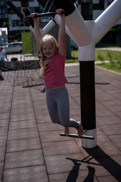 Life of children in a modern city - the girl is having fun on the playground near the house — Stock Photo, Image