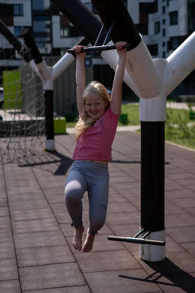 Life of children in a modern city - the girl is having fun on the playground near the house — Stock Photo, Image