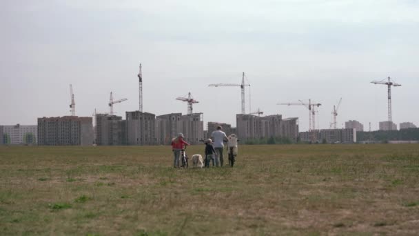 Estilo de vida saludable - familia con bicicletas y un perro paseando por el campo cerca de la ciudad — Vídeos de Stock