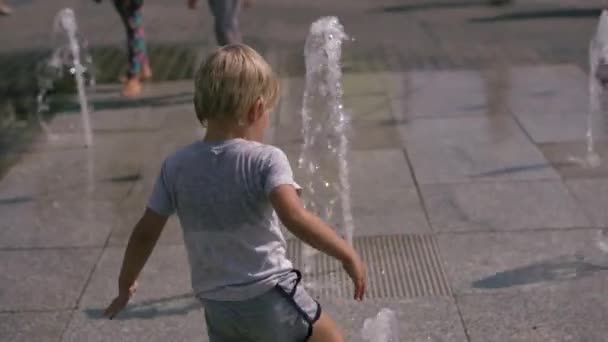 La vida moderna en un mundo grande - los niños se divierten corriendo por la fuente de la ciudad — Vídeo de stock