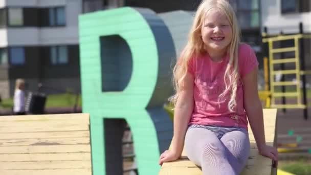 Leben der Kinder in einer modernen Stadt - das Mädchen vergnügt sich auf dem Spielplatz neben dem Haus — Stockvideo