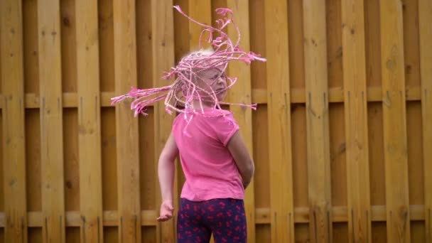 Stylish girl waving African pigtails near a brick wall - slow motion — Stock Video