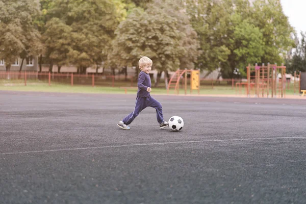 Estilo de vida ativo em uma cidade moderna - menino brincando com uma bola de futebol no estádio — Fotografia de Stock