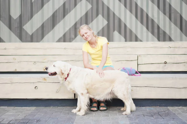 Amor por las mascotas - una joven rubia descansando con su perro en la calle —  Fotos de Stock