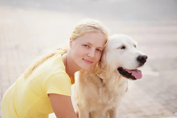 Amor por las mascotas - una joven rubia descansando con su perro en la calle —  Fotos de Stock