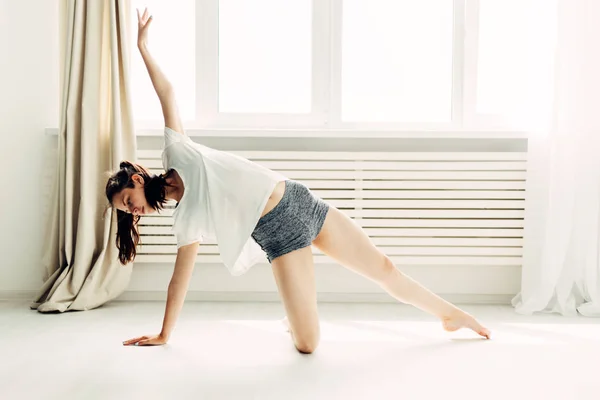 Jovem menina bonita fazendo aquecimento contemporâneo em casa — Fotografia de Stock