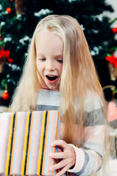 Chica con un regalo de Navidad cerca de un árbol de Navidad —  Fotos de Stock