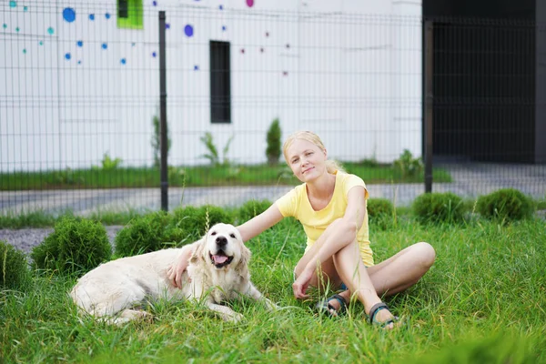 Amor por las mascotas - una joven rubia descansando con su perro en la hierba —  Fotos de Stock