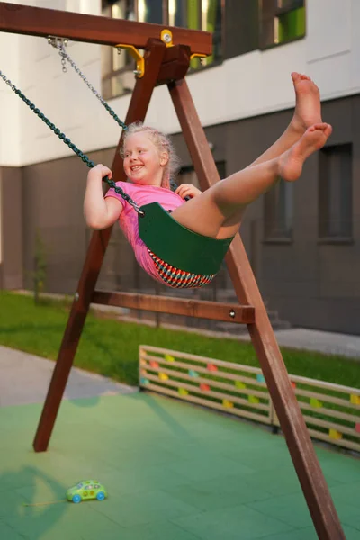 Life of children in a modern city - the girl is having fun on the playground near the house — Stock Photo, Image