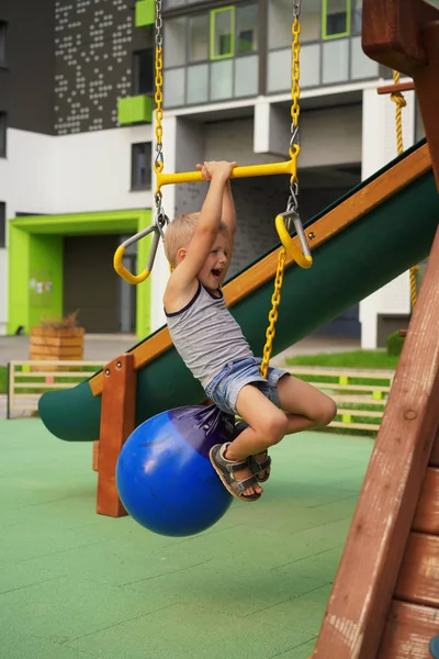 Life of children in a modern city - little boy is having fun on the playground near the house — Stock Photo, Image