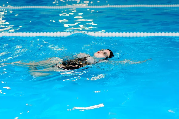 Clases de natación para niños en la piscina - hermosa chica de piel clara nada en el agua — Foto de Stock