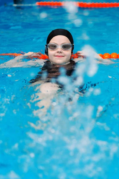 Swimming lessons for children in the pool - beautiful fair-skinned girl swims in the water — Stock Photo, Image