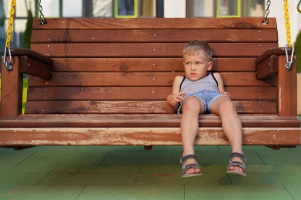 La vida de los niños en la ciudad moderna - el chiquitín descansa en el banco en el patio de recreo — Foto de Stock