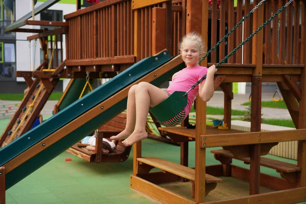 Life of children in a modern city - the girl is having fun on the playground near the house — Stock Photo, Image