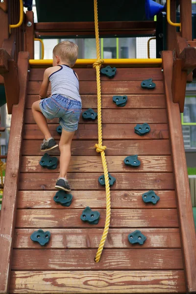 Life of children in a modern city - little boy is having fun on the playground near the house — Stock Photo, Image