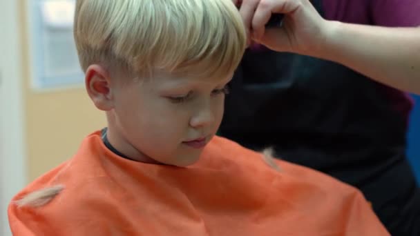 Frisyr för en liten pojke i en barnens frisörsalong — Stockvideo