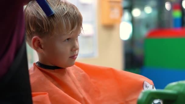 Corte de pelo de un niño en un salón de peluquería para niños — Vídeos de Stock