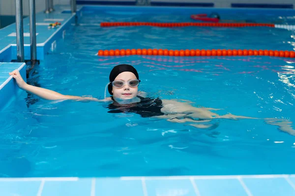 Swimming lessons for children in the pool - beautiful fair-skinned girl swims in the water — Stock Photo, Image