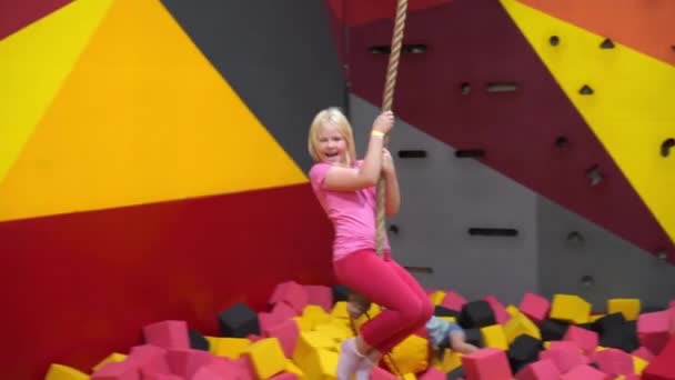 Счастливое детство современного ребенка в городе - девочка в парке развлечений верхом на веревке — стоковое видео