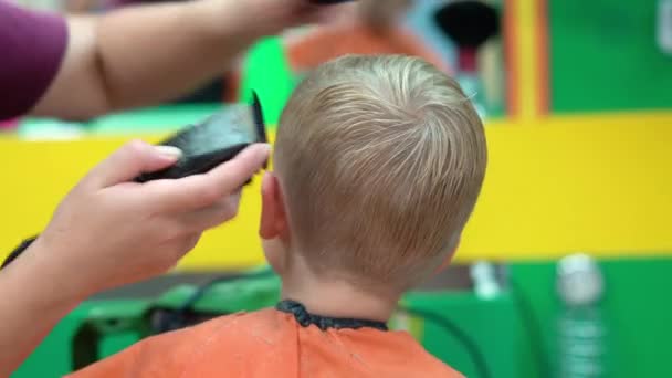 Corte de pelo de un niño en un salón de peluquería para niños — Vídeo de stock