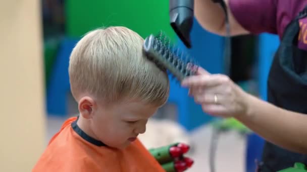 Corte de cabelo de um menino em um salão de cabeleireiro de crianças — Vídeo de Stock