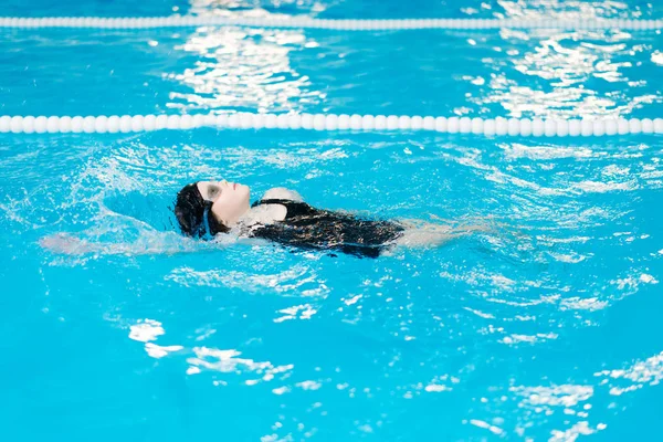 Swimming lessons for children in the pool - beautiful fair-skinned girl swims in the water — Stock Photo, Image