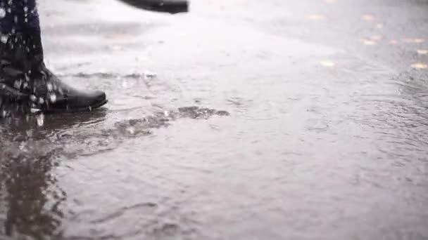Девушка в черных кожаных сапогах ходит по осенней луже во время дождя в замедленном движении — стоковое видео