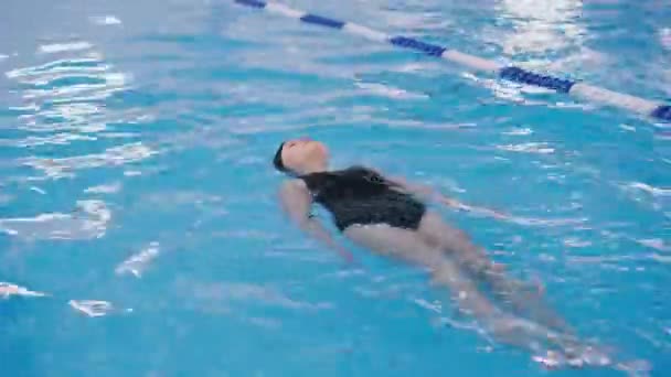 Úszásoktatás, a gyermekek számára a medencében - szép bőrű lány úszik a vízben — Stock videók