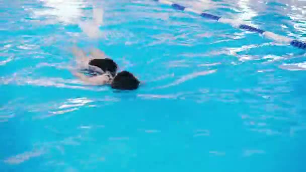 Clases de natación para niños en la piscina - hermosa chica de piel clara nada en el agua — Vídeo de stock