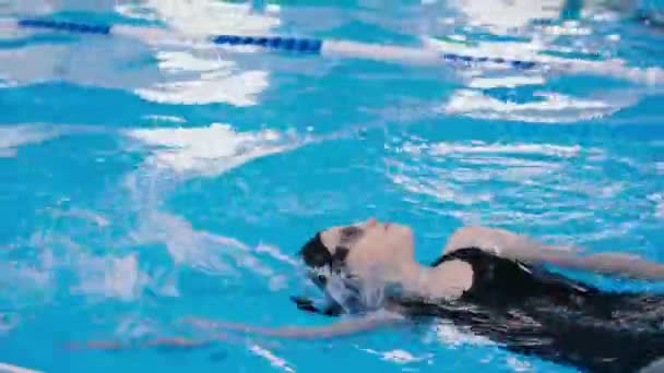 Lezioni di nuoto per bambini in piscina - bella ragazza dalla pelle chiara nuota in acqua — Video Stock