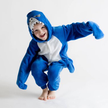 neşeli küçük çocuk pijama, mavi köpekbalığı kostüm beyaz bir arka plan üzerinde poz