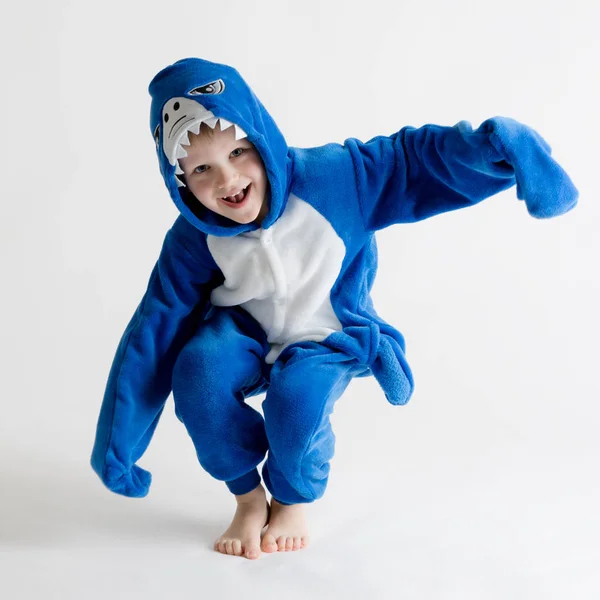 Fröhlicher kleiner Junge posiert auf weißem Hintergrund im Schlafanzug, blauem Hai-Kostüm — Stockfoto