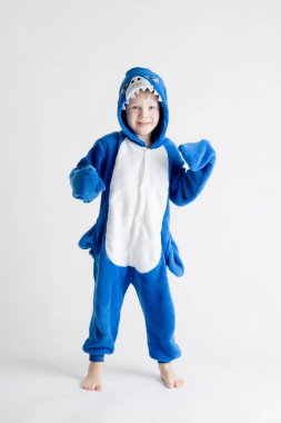 neşeli küçük çocuk pijama, mavi köpekbalığı kostüm beyaz bir arka plan üzerinde poz.