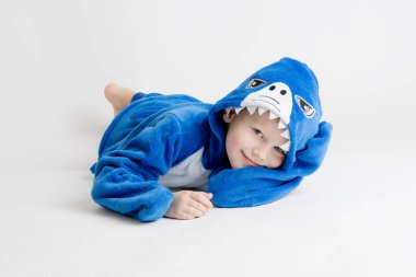 neşeli küçük çocuk pijama, mavi köpekbalığı kostüm beyaz bir arka plan üzerinde poz