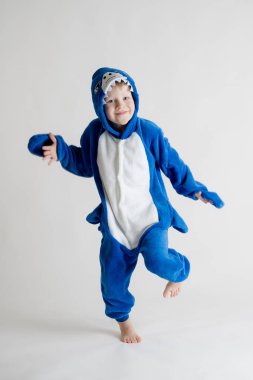 neşeli küçük çocuk pijama kigurumi, mavi köpekbalığı kostüm beyaz bir arka plan üzerinde poz