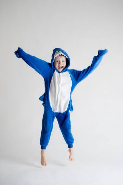 neşeli küçük çocuk pijama, mavi köpekbalığı kostüm beyaz bir arka plan üzerinde poz
