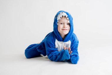 neşeli küçük çocuk pijama, mavi köpekbalığı kostüm beyaz bir arka plan üzerinde poz