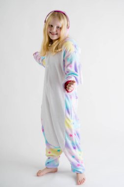 Modern moda - güzel sarışın kız kigurumi pijama beyaz bir arka plan üzerinde kulaklık ile müzik dinler