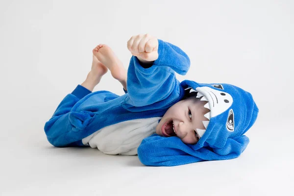 Χαρούμενο μικρό αγόρι ποζάρει σε λευκό φόντο με τις πυτζάμες, shark μπλε κοστούμι Royalty Free Φωτογραφίες Αρχείου