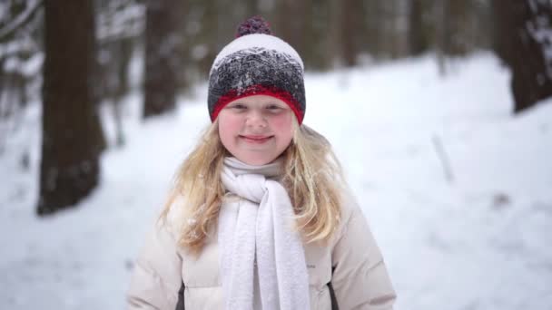 Портрет красивой блондинки в зимнем лесу с падающим снегом - видео замедленного движения — стоковое видео