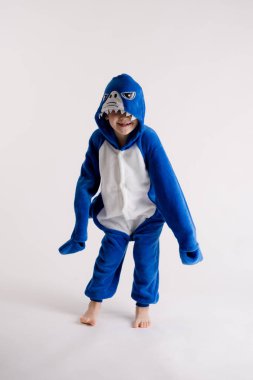 neşeli küçük çocuk pijama, mavi köpekbalığı kostüm beyaz bir arka plan üzerinde poz