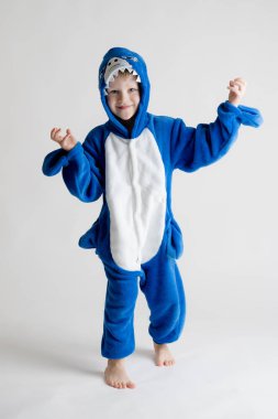 neşeli küçük çocuk pijama kigurumi, mavi köpekbalığı kostüm beyaz bir arka plan üzerinde poz