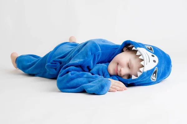 Cheerful little boy posing on a white background in pajamas, blue shark costume — Stock Photo, Image